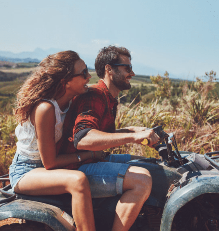 man and woman riding a motorcycle together on a sunny day