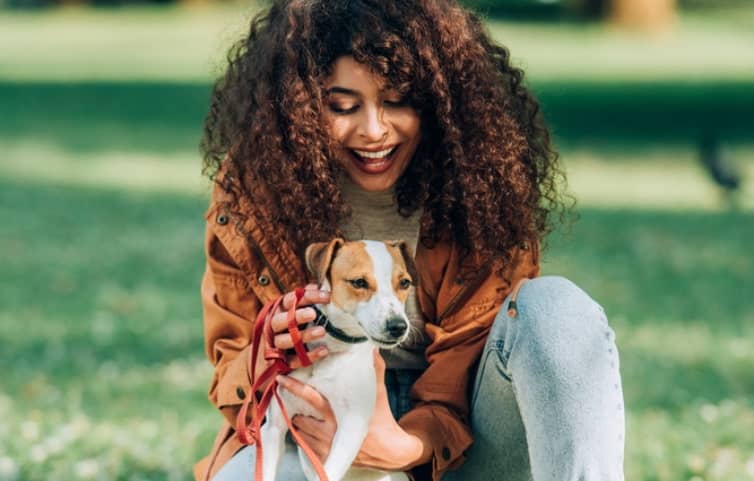 happy woman with dog in a park playing