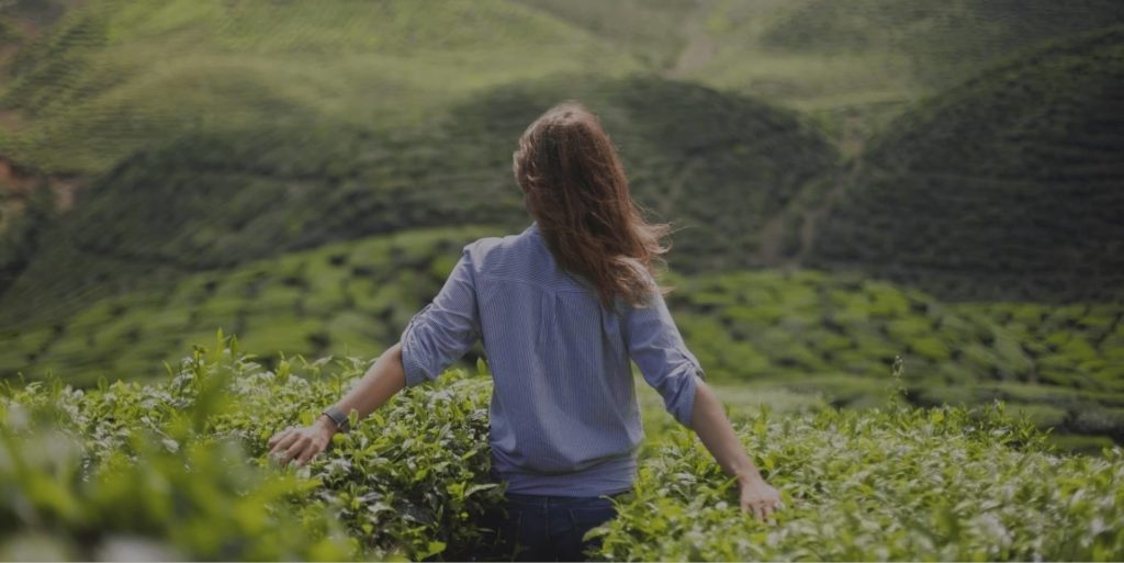 woman standing in tall shrubs in beautiful landscape