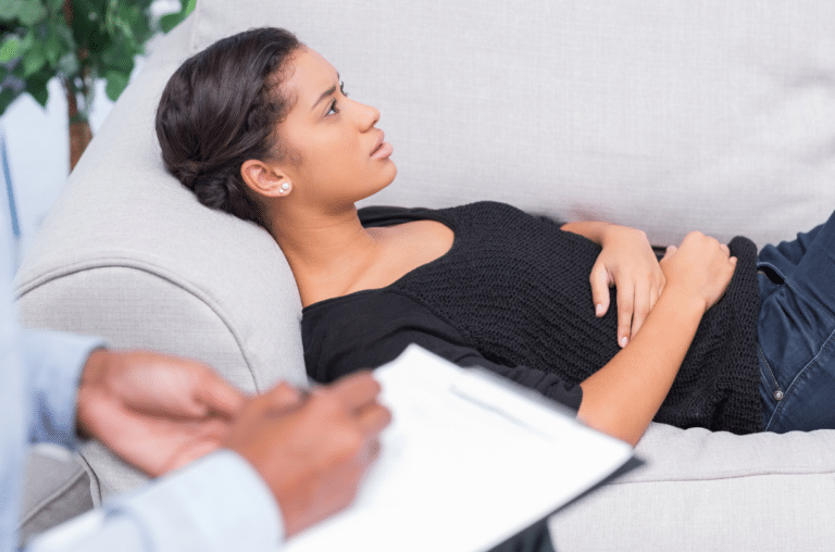 woman laying on couch while therapist takes notes
