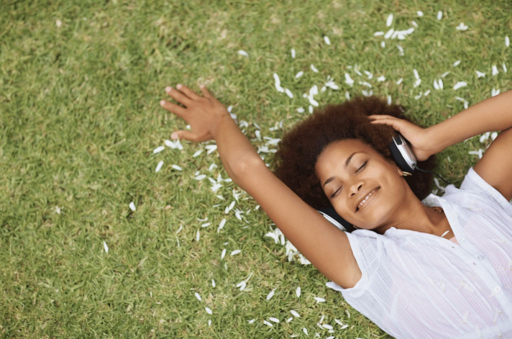 woman laying on grass talking on phone while smiling