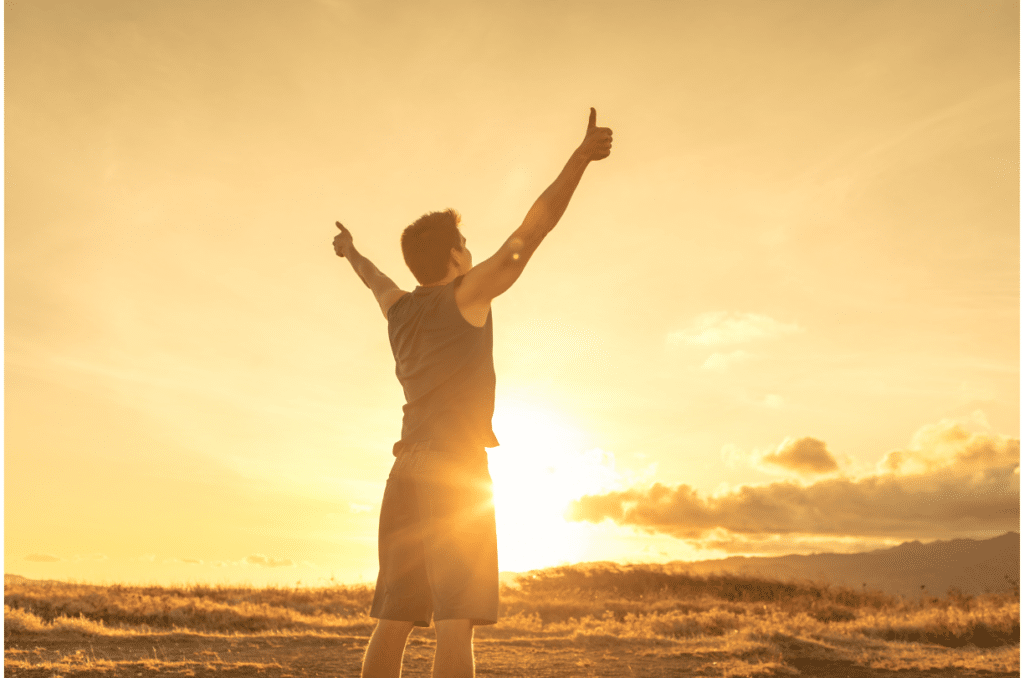 accomplished man standing outside with hands up