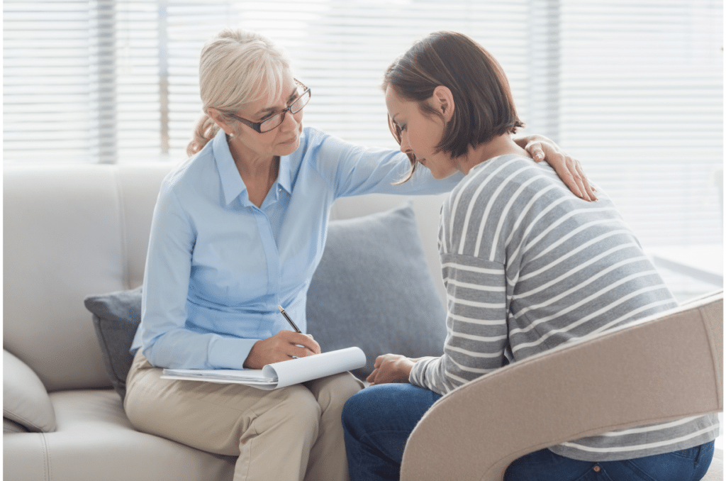 woman therapist with hand on shoulder on female client