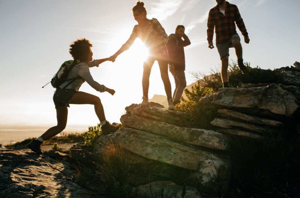 group of hikers helping each other climb