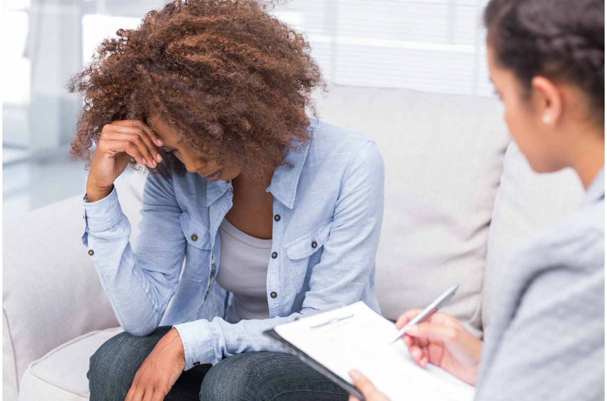 distressed woman looking down in therapy