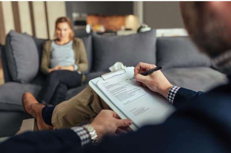 therapist takes notes in therapy session while client talks