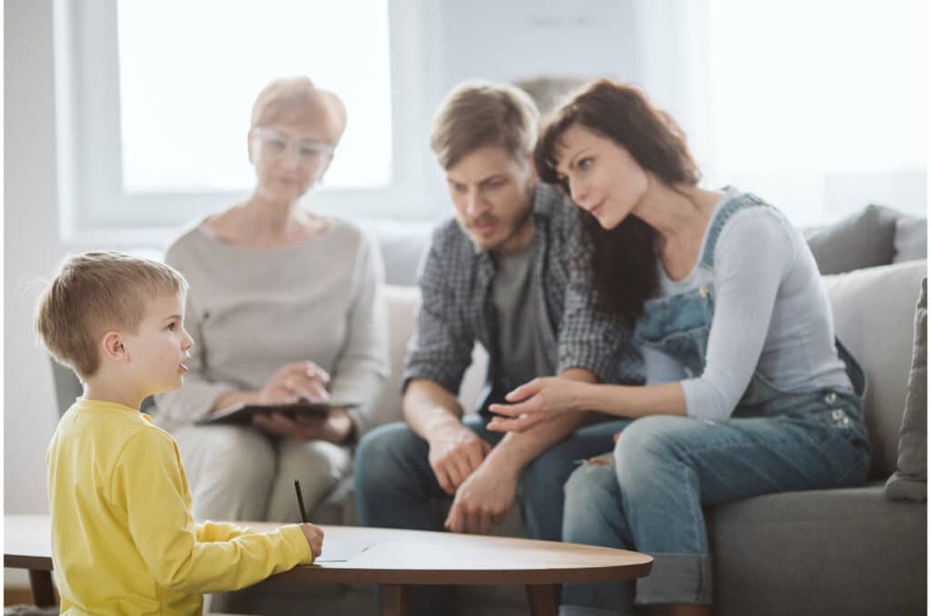 three human adults talking to a little boy