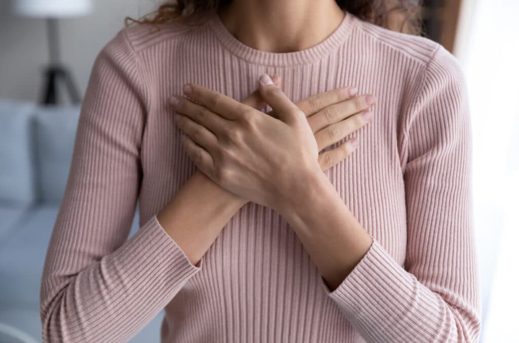 woman holding hands over her heart