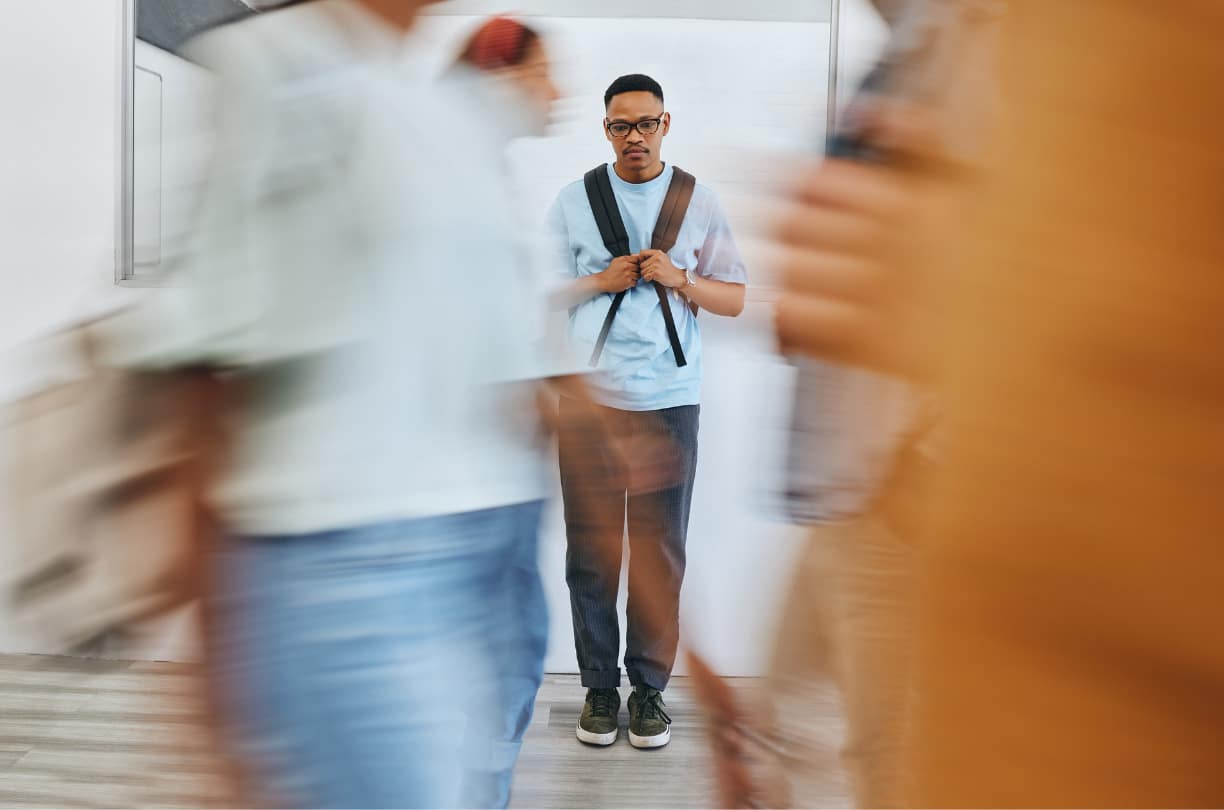 lonely man standing in hallway at school while people pass