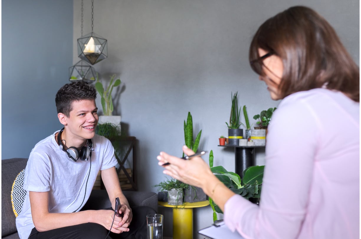 teenage boy smiling at therapist while she talks