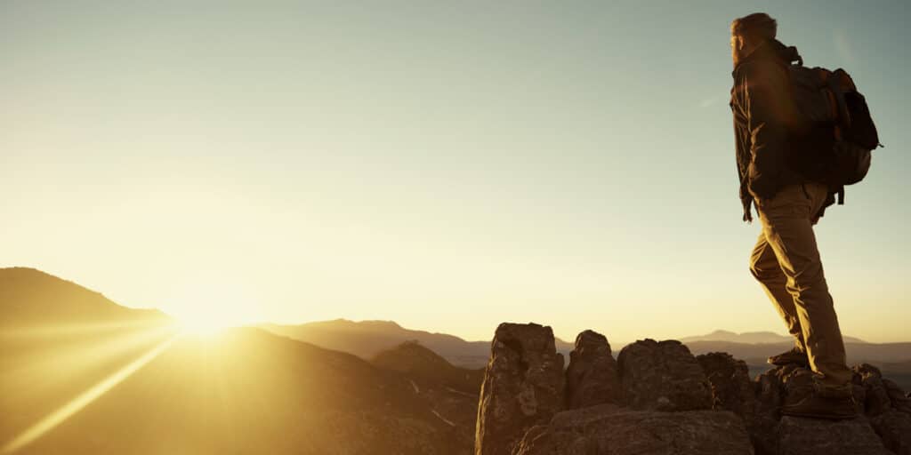 man hiking on rocks during sunrise