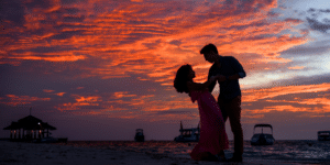 couple dancing on the beach together at sunset