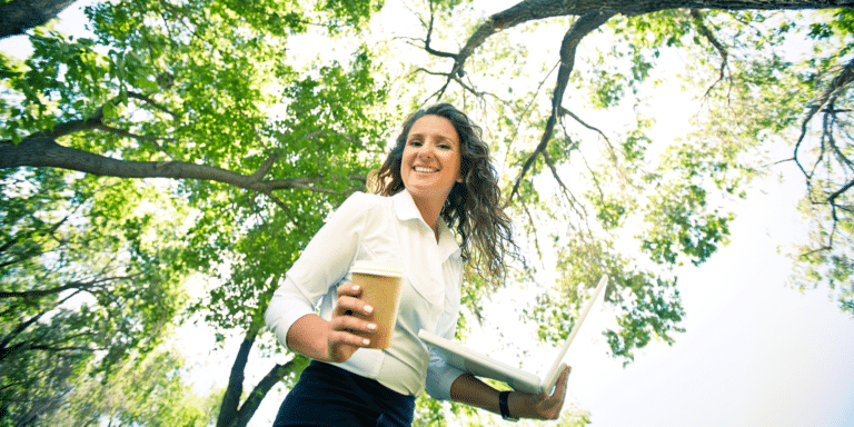 happy woman smiling outside with her coffee