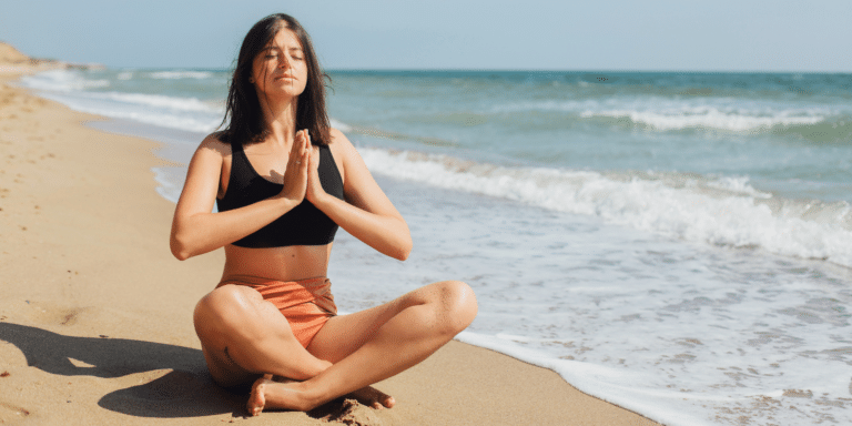 woman meditating on the beach
