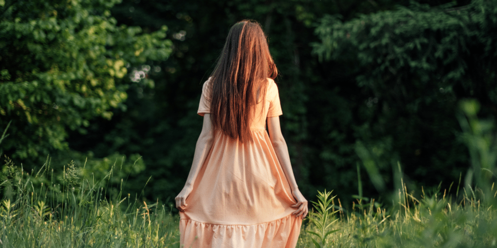 woman in peace walking through the grass and forest