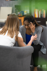 stressed woman holding her head while her therapist tries to help her