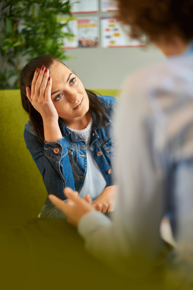 woman holding her hand to her head while talking to her therapist