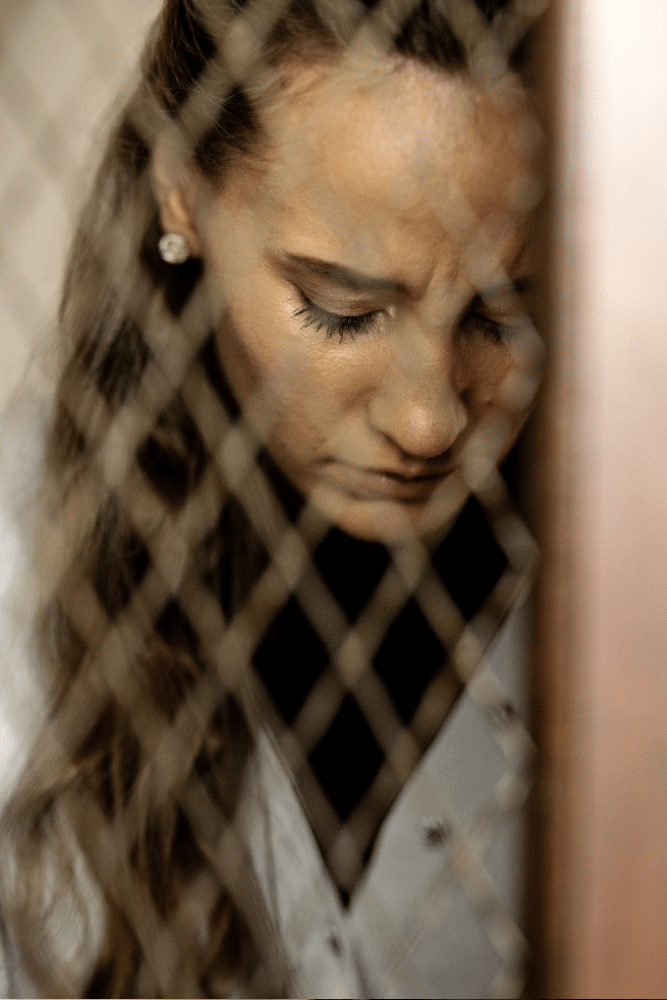 woman sad looking down through a wires pattern