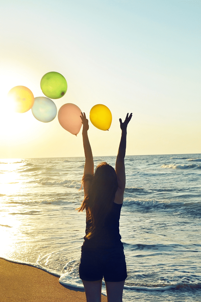 happy woman on the beach releasing balloons into the sky, freedom