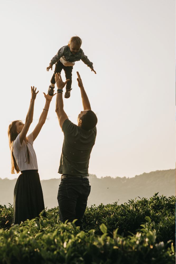 happy couple throwing their baby up into the air outside