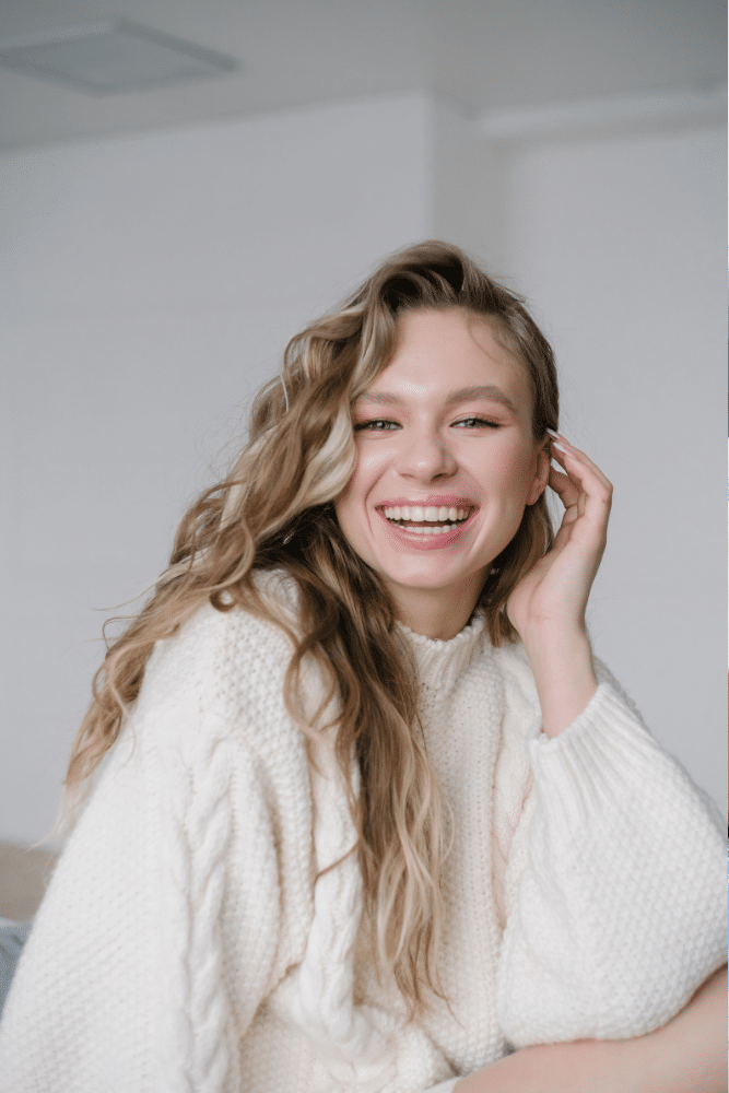 girl in a white shirt smiling with her hand on her face