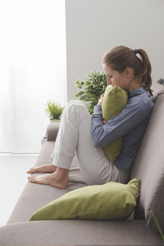 woman sitting on therapy couch with knees up and hugging a pillow