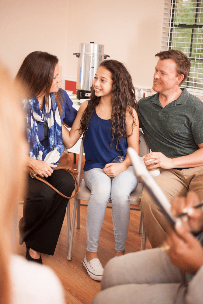 teenager and both her parents smiling in a counseling session, family therapy