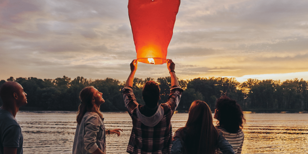 group of teenagers lighting a red lantern to send over the lake, happiness in group time