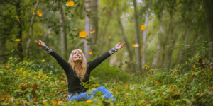 woman throwing leaves up into the air and smiling