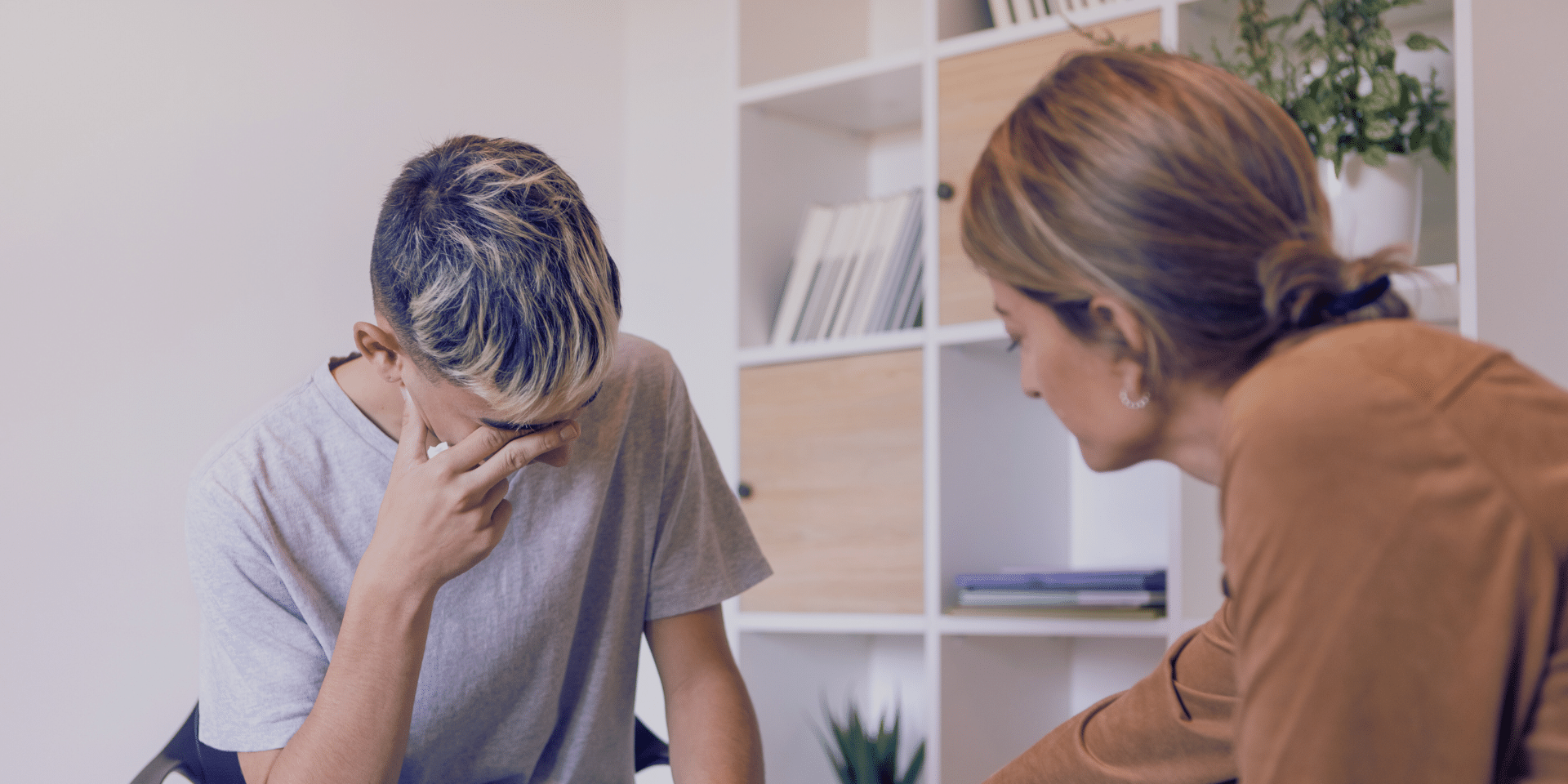 lady therapist talking to teenage boy who looks distressed