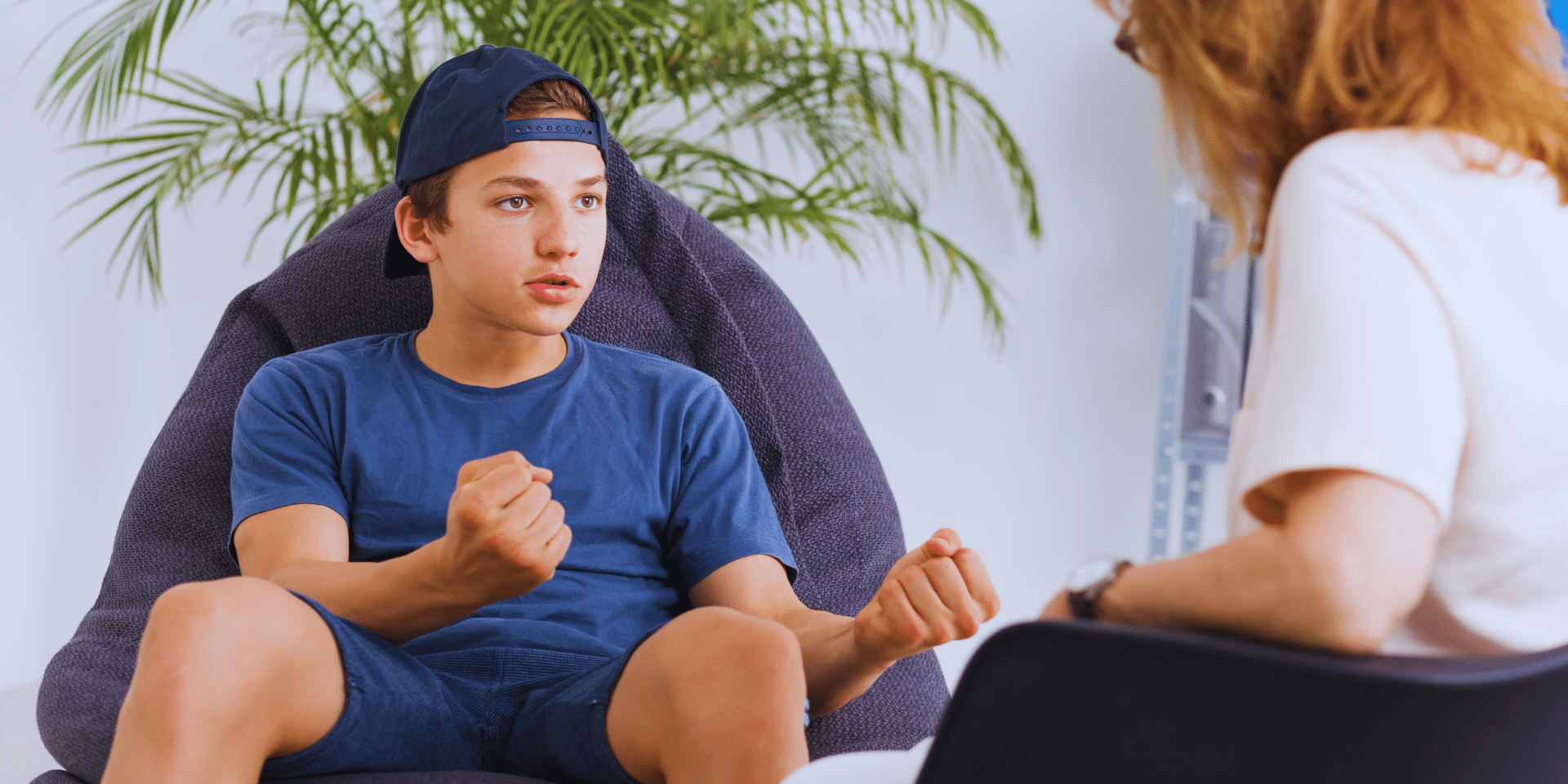 boy holding up his fists to the therapist as he talks