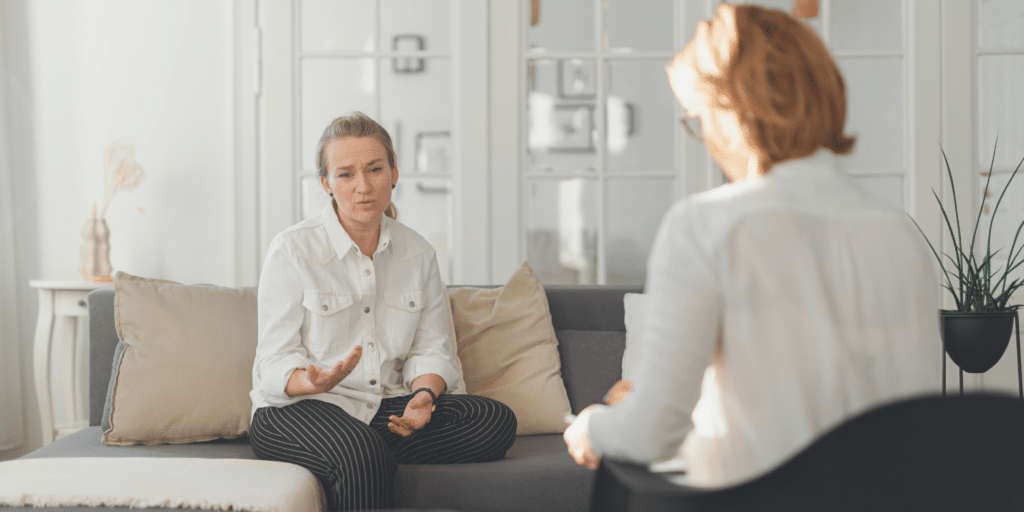 woman client talking with her woman therapist while sitting on a couch and explaining herself