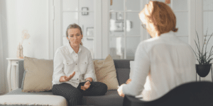 woman client talking with her woman therapist while sitting on a couch and explaining herself