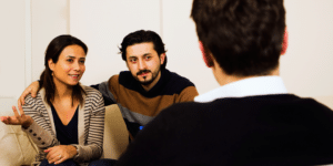 couple in counseling together, smiling and hugging while talking to the therapist