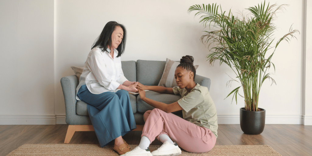 therapist consoling her client by grabbing her hands and reassuring her, on the couch