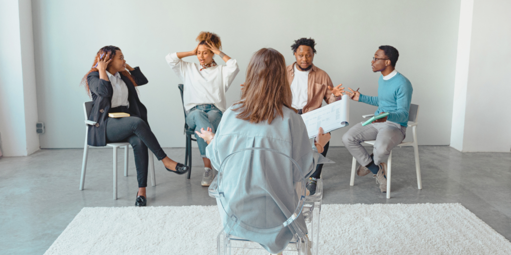 group counseling session, clients are grabbing their heads and looks a little chaotic. one therapist