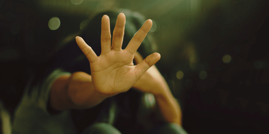 hand reaching out toward the camera, symbolizing either "help" or "stop"