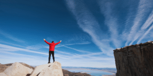 man standing on top of a mountain with arms stretched wide, freedom and joy