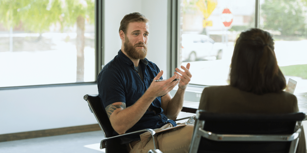 man client sitting in a chair and talking to his female therapist