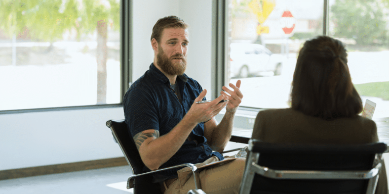 man client sitting in a chair and talking to his female therapist