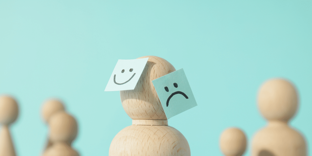 wooden figure with a happy face and a sad face paper on it's face