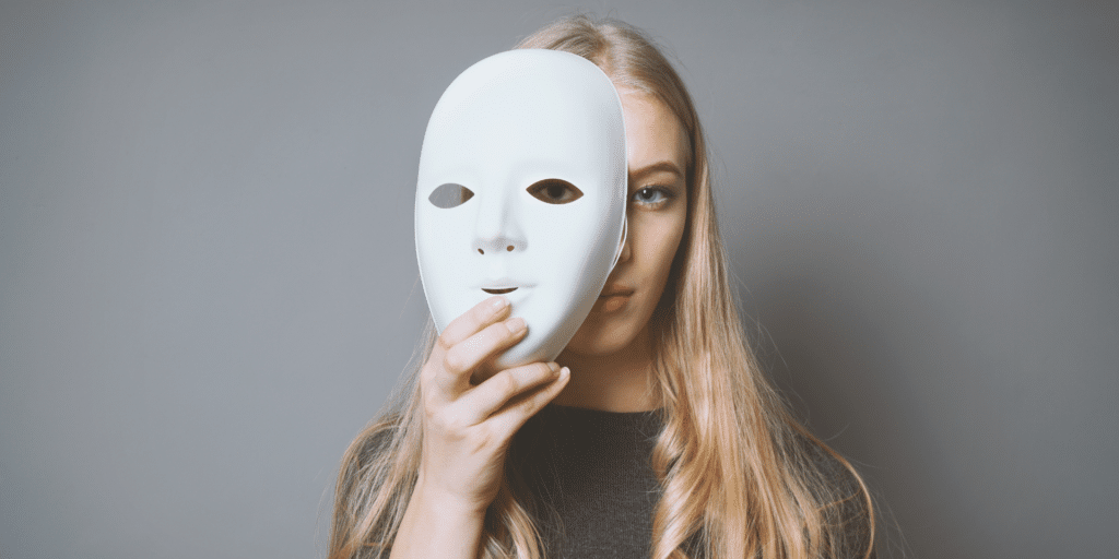 woman holding up a mask to her face to represent dealing with bipolar disorder