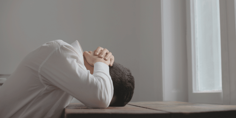 man feeling stressed and overwhelmed with his head laid down on his desk