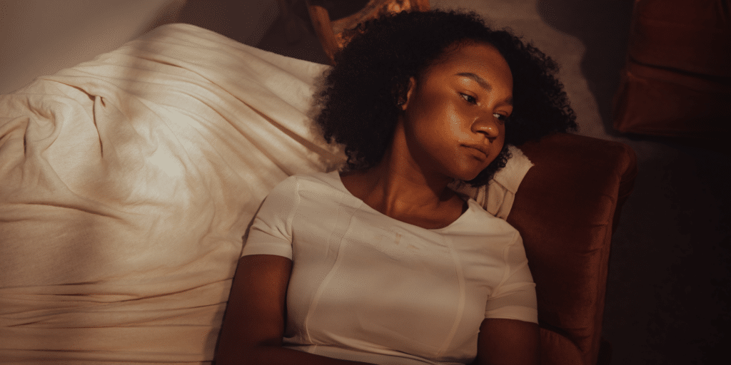 lady laying on her bed in the dark looking pretty sad and depressed