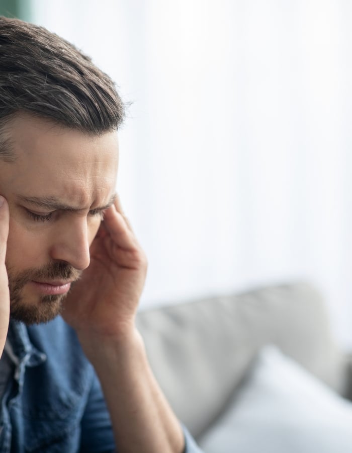 Stressed man holding his head in his hands, representing anxiety, burnout and stress counseling