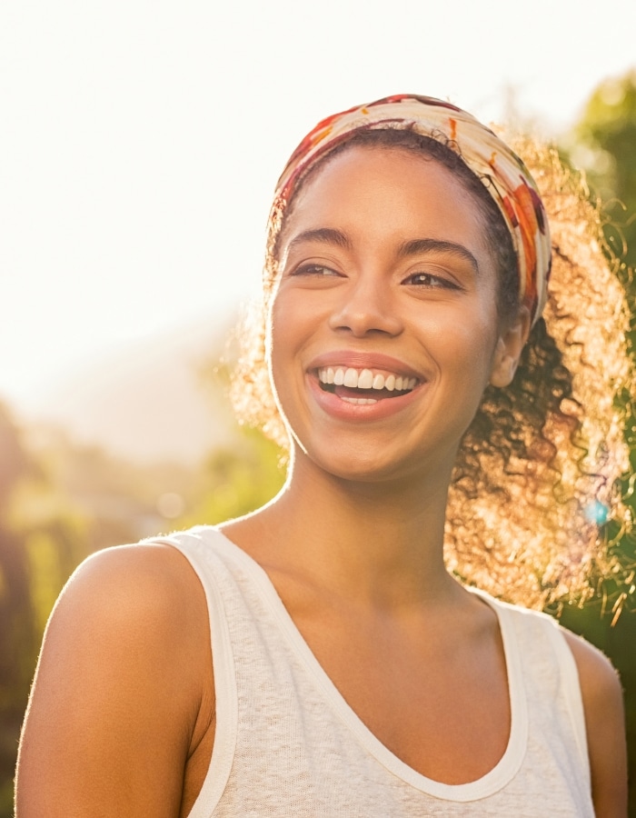 Black woman laughing in warm sunlight, representing emotional wellness after counseling