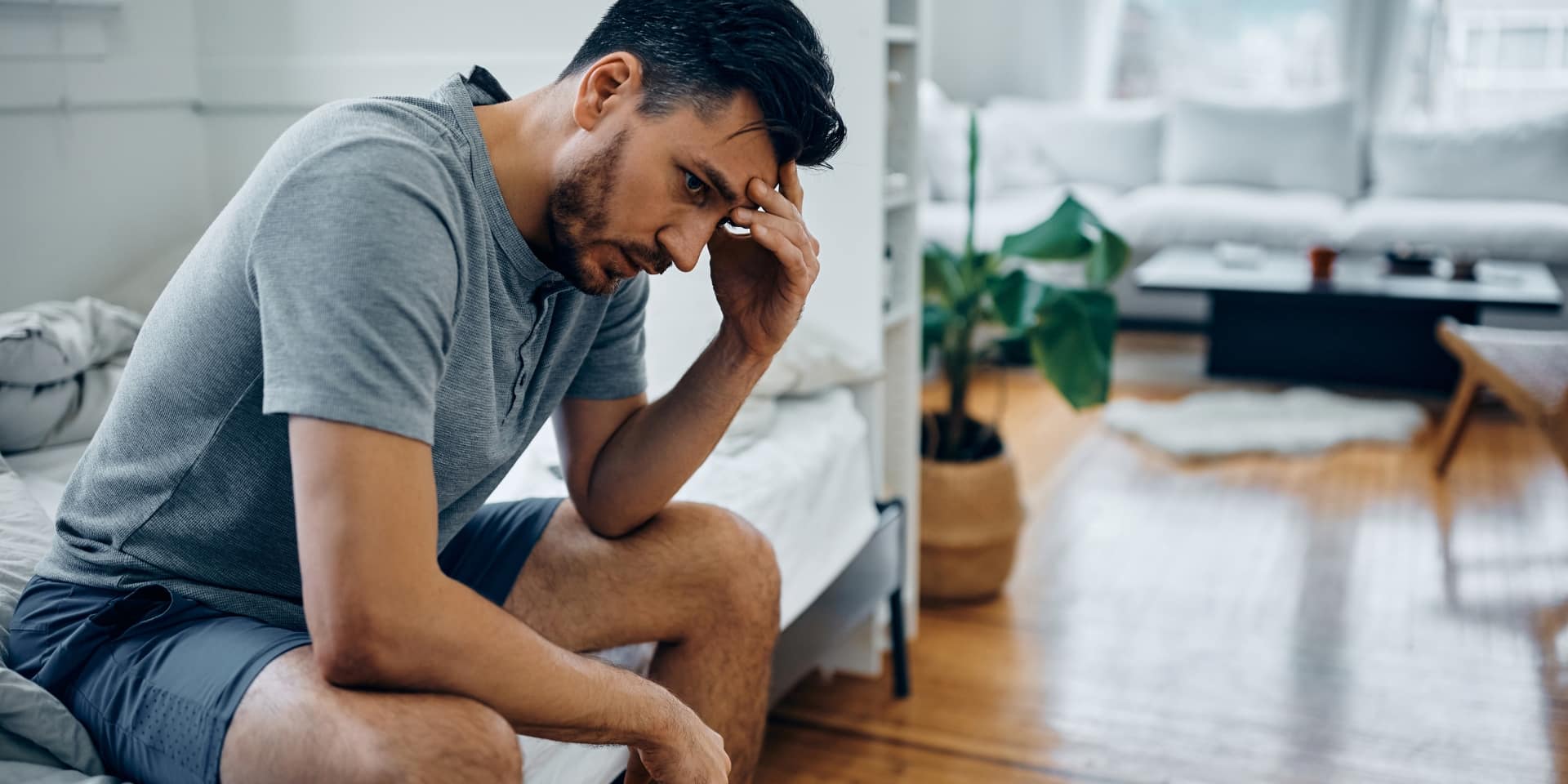 Man sitting on the edge of his bed with his head in his hand, representing depression counseling