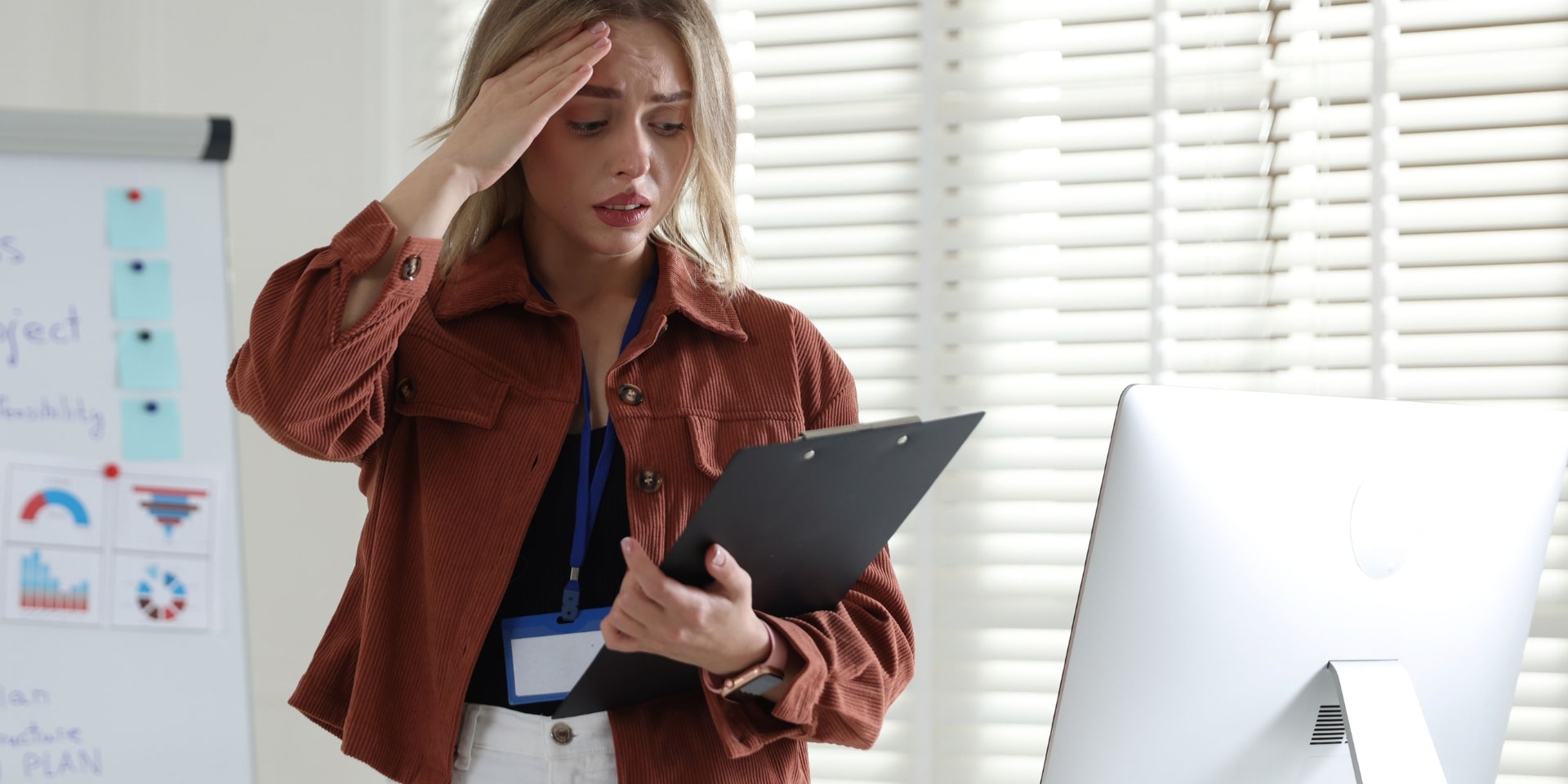 Overwhelmed professional woman holding a clipboard at the office, a sign of high-functioning anxiety