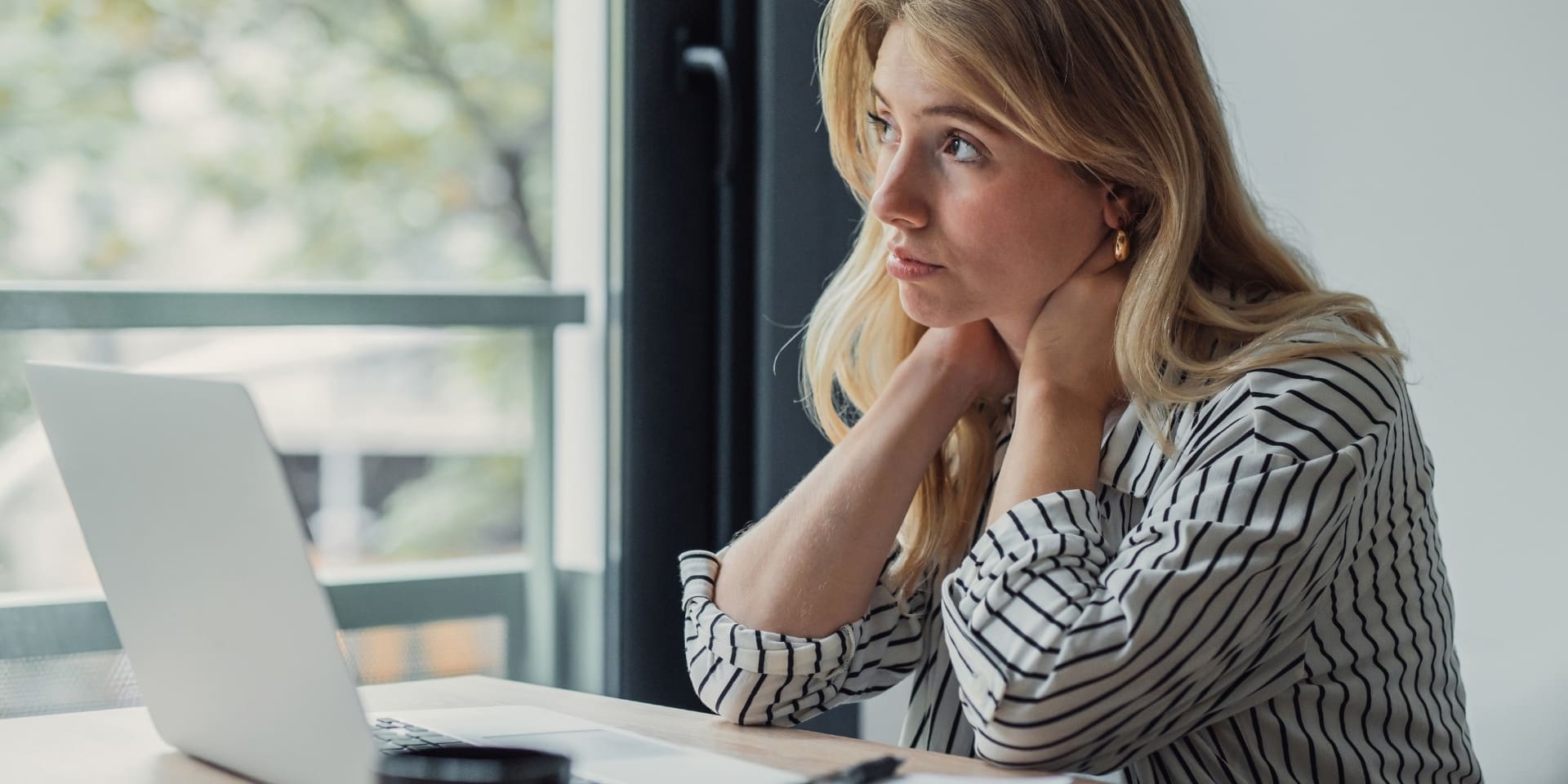 Professional woman staring out the window at her laptop, representing high-functioning depression therapy in Denver
