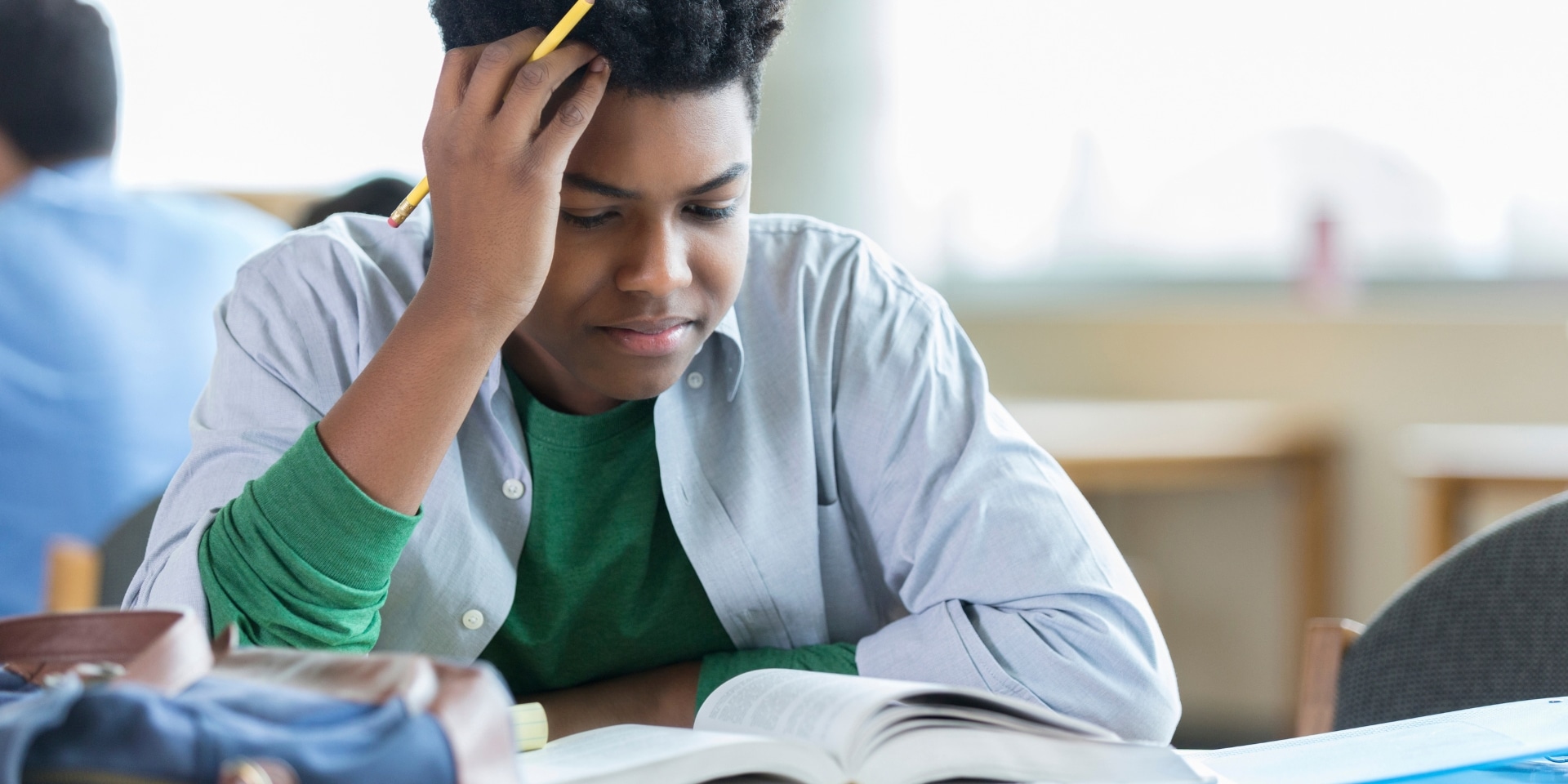 Teen boy stressed while studying in class, representing therapy for high-achieving teens in Denver